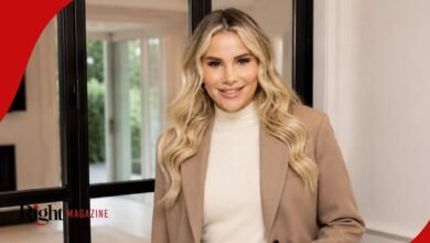 Georgia Kousoulou smiling while wearing a neutral tan blazer and off-white turtleneck sweater inside a modern home.