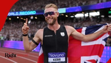 Josh Kerr wearing his black Great Britain kit and running sunglasses, smiling and celebrating on the track while holding the Union Jack flag.