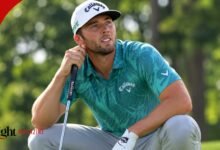 PGA Tour golfer Sam Burns squatting on the green, wearing a teal patterned Callaway polo and white cap while holding his putter.
